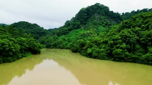 A serene lake nestled within a dense forest, surrounded by towering green mountains.