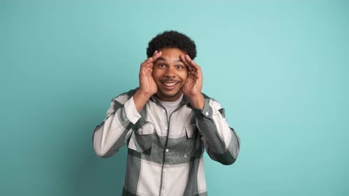 Stunned Young Man Smiling at Camera in Blue Studio