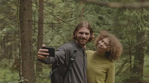 Young Couple Taking Selfie with Phone in Forest during Hike