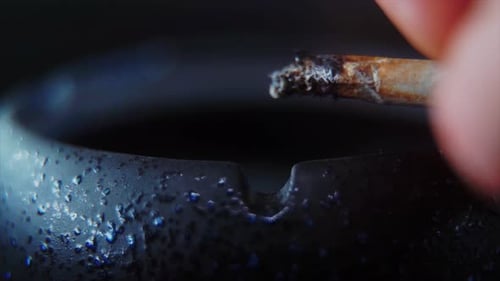 Eine Makro-Nahaufnahme von Ascheresten einer Zigarette in einem schwarzen Steinaschenbecher, 4K-Video in Zeitlupe