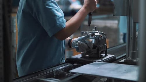 Ouvrier industriel assemblant des appareils métalliques sur un convoyeur automatique en usine. Gros plan du moteur...