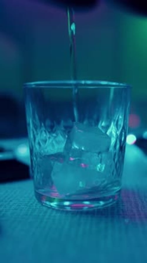 Pouring a Drink in a Neon Lit Bar at Night