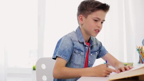 Boy doing homework at desk in bright room