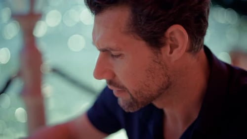 Close-up of a thoughtful man with a beard drinking coffee from a white cup