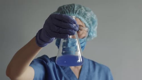 Scientist Analyzing Liquid in Beaker in Lab