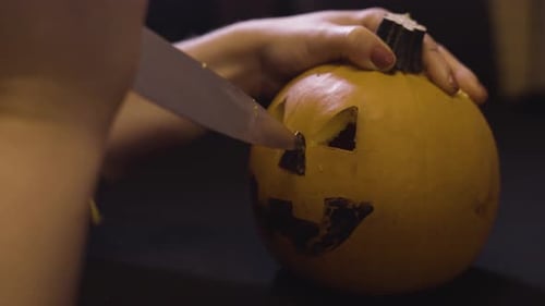 Hände, die für Halloween Löcher in einen Kürbis schnitzen — Nahaufnahme