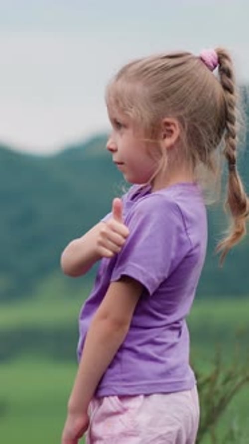 Adorable Girl with Plait Shows Thumbup in Mountain Valley