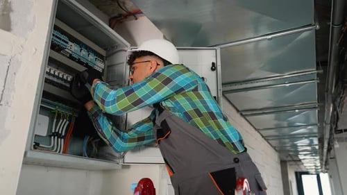 Electrician Repairing Electrical Panel in Modern Building