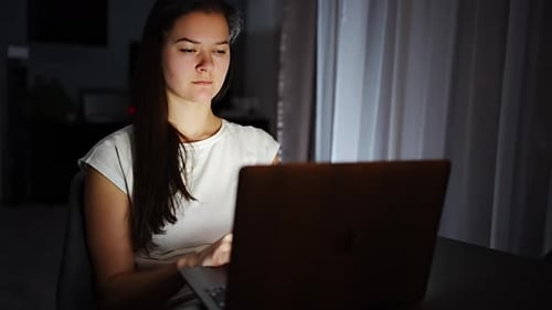 Woman Using Laptop Computer at Night Indoors
