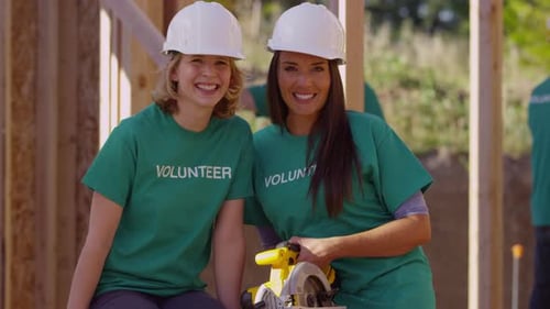 Volunteers smiling near construction site on a sunny day