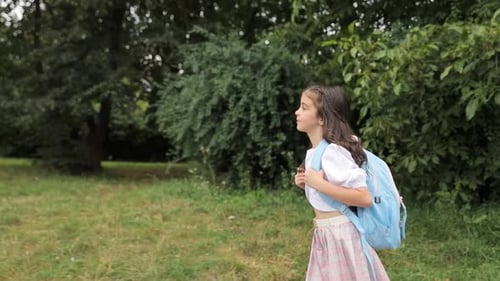 Ein kleines Mädchen mit einem blauen Rucksack auf den Schultern geht zur Schule und lernt in der Schule