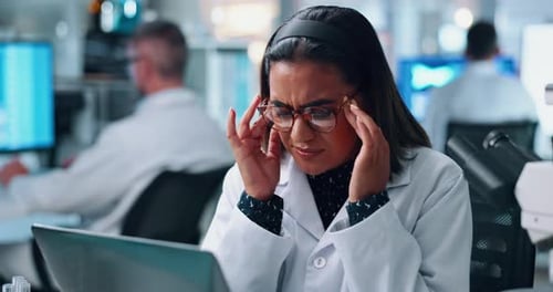Female Scientist Rubbing Temples in Lab