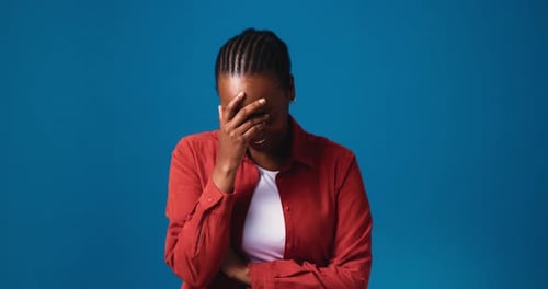 Happy, black woman and laughing with face in studio for funny joke or humor on a blue background