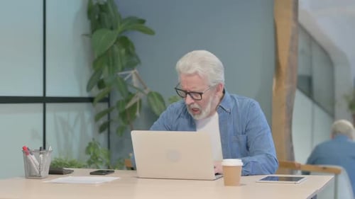 Senior Man Coughing While Working at Laptop
