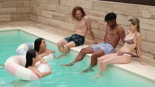 Friends enjoying summer holidays chatting in a swimming pool