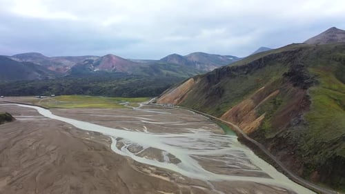 An aerial view of a high mountain area where rivers flow through sandy landscapes between mountains.