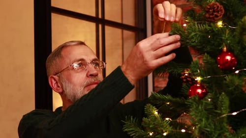 an Elderly Man in a Green Knitted Decorating the Christmas Tree