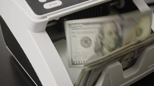 Money Counting Machine Counts Stack of US Dollars