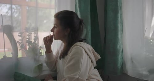 Woman Looking Out Window on Sunny Day