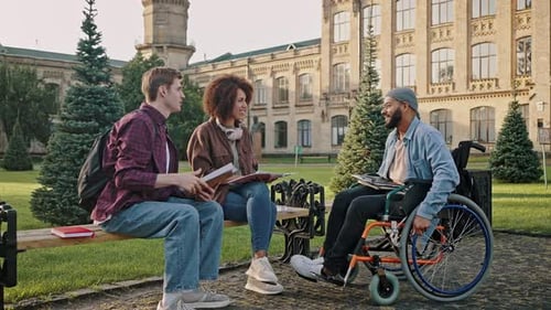 Un homme en fauteuil roulant conduit vers des amis en faisant un geste de poing