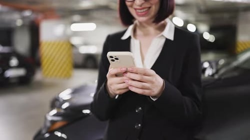 Businesswoman Typing on Smartphone in Indoor Car Park