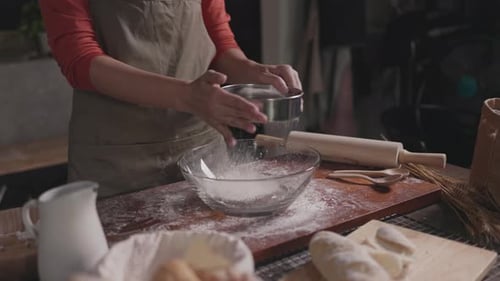 baker sift flour with sifter on kitchen table at traditional at bakery