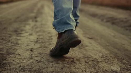Rubber Boots Walking Legs Rural Dirty Road Field at Countryside. Close Up Shoes Unknown Farmer Ag...