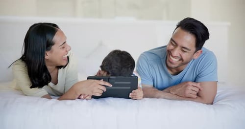 Family Watching Tablet in Bed Together and Laughing