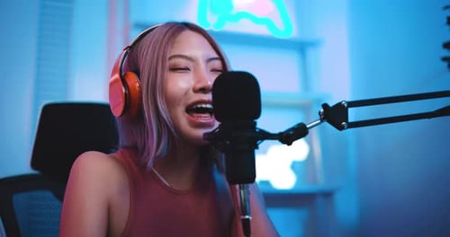 Young Woman Singing Into Microphone With Headphones