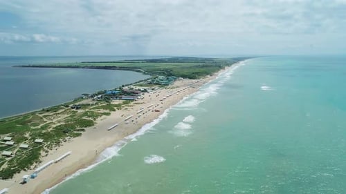 Aerial Over the Long Sandy Spit with a Beach and Azure Water on a Sunny Summer Day Waves Crashing to