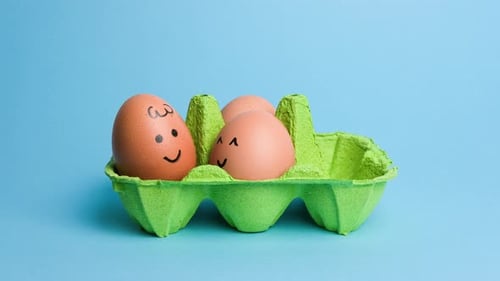 Cute Easter Eggs with Funny Faces in Green Box Isolated on Blue Background
