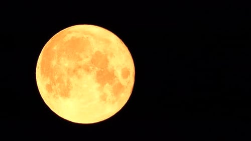 Ein glühender goldener riesiger Vollmond von der Erde aus gesehen durch die Atmosphäre vor einem sternenklaren Nachthimmel