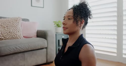Mulher afro-americana com o braço direito estendido, torso giratório, estendendo a mão na sala de estar, se alongando