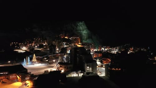 Winter ski resort village and hotels lit-up at night, aerial view