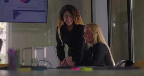 Junge Frau und blonde Kollegin überprüfen während des Teams gemeinsam Computerdaten im Konferenzraum