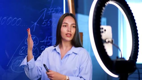 Young Woman Explaining Data Next to Glowing Ring Light