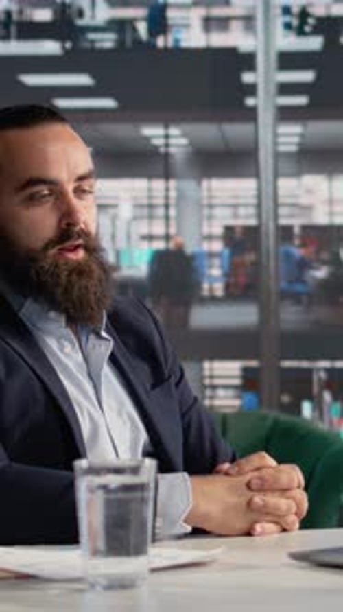 Bearded Man In Meeting Talking At Office Desk