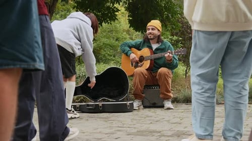 Hombre callejero agradeciendo a una chica por la propina mientras canta en un parque público