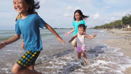 A happy Asian family playing and having fun on the beach in slow motion