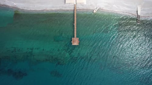 Wooden Pier Stretching into Clear Turquoise Water – Aerial View