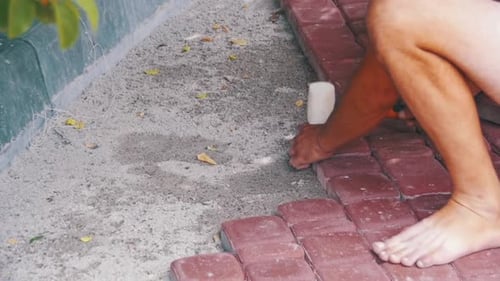 Man Laying Red Brick Pavers With Mallet