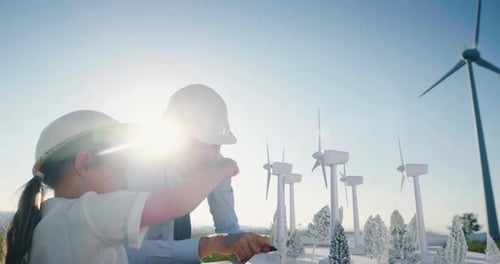 Um pai engenheiro mostra seu projeto para a filha para a construção de um parque eólico. A filha