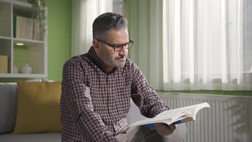 Man Reading a Book on the Couch Indoors