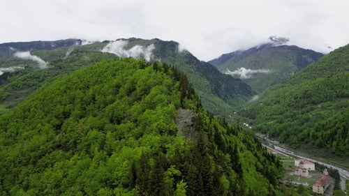 Drone shot over green mountains with cloudy sky