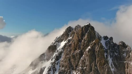 Aerial View Of A Snowy Mountain Peak Above Clouds. British Columbia, Canada.