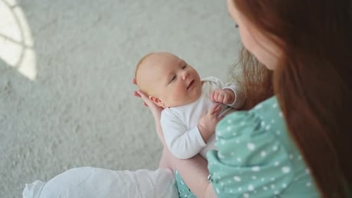 Loving Mother Holding Newborn Infant in Bright Home