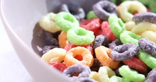 Breakfast cereal falling into bowl on table, closeup