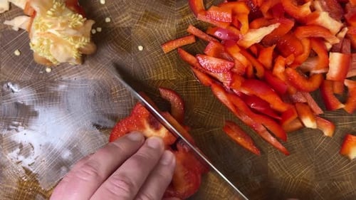 Cutting Red Bell Pepper Into Strips on Wood