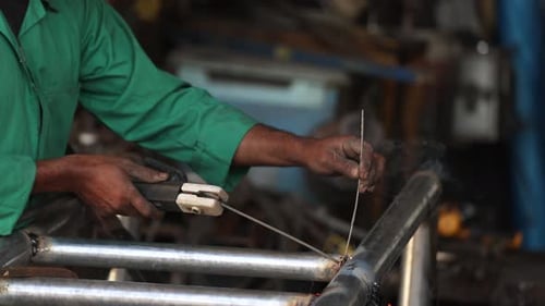 Craftsman Welding Metal Tubes in Workshop