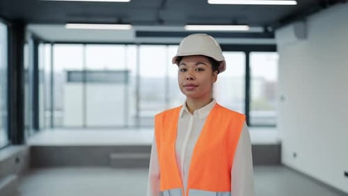 Engenheira confiante com capacete e colete de segurança sorri em um escritório moderno